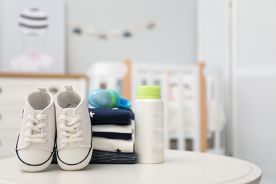 Photo of Stack of baby clothes, shoes and accessories on white table indoors