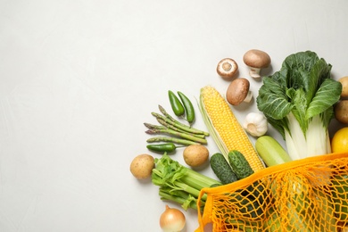 Fresh vegetables in eco mesh bag on white background, flat lay. Space for text