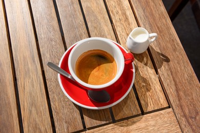 Cup of aromatic hot coffee and milk on wooden table, above view
