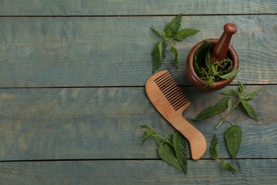 Photo of Stinging nettle and comb on blue wooden background, flat lay with space for text. Natural hair care
