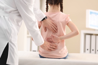 Chiropractor examining child with back pain in clinic, closeup