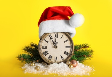Vintage alarm clock with Christmas decor on yellow background. New Year countdown