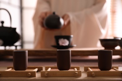 Master conducting traditional tea ceremony at table indoors, focus on cups