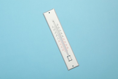 Weather thermometer on light blue background, top view