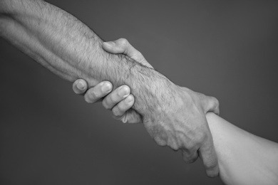 Men holding hands together on grey background, black and white effect. Unity concept