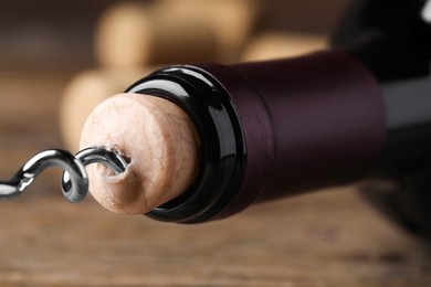 Opening wine bottle with corkscrew on background, closeup