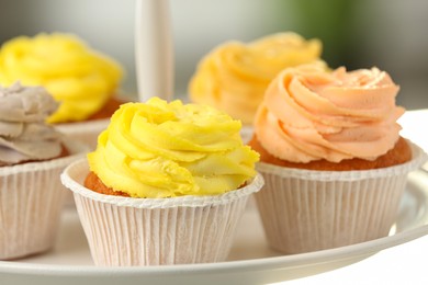 Photo of Tasty cupcakes with cream on dessert stand, closeup