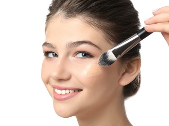 Photo of Beautiful girl applying foundation with brush on white background. Face contouring