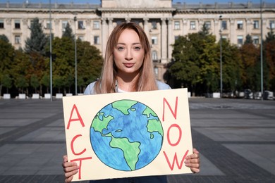 Young woman with poster protesting against climate change on city street
