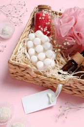 Photo of Spa gift set of different luxury products in wicker basket on pale pink background