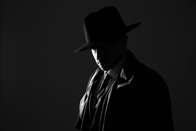 Old fashioned detective in hat on dark background, black and white effect. Space for text