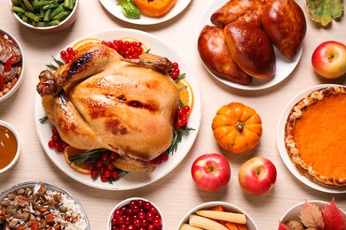 Traditional Thanksgiving day feast with delicious cooked turkey and other seasonal dishes served on wooden table, flat lay