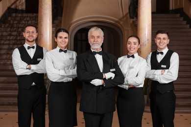 Photo of Group of young trainees with teacher in hotel. Professional butler courses