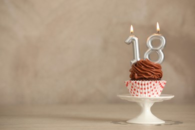 18th birthday, coming of age party. Delicious cupcake with number shaped candles on beige table, space for text