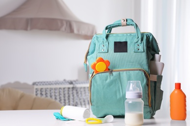 Maternity backpack with baby accessories on table indoors. Space for text