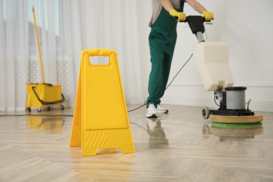 Professional janitor cleaning parquet floor with polishing machine indoors, closeup