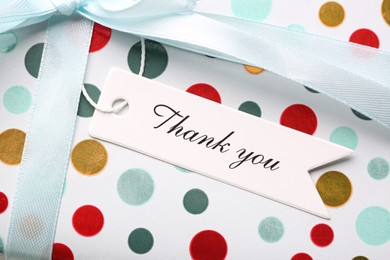 White tag with phrase Thank You on gift box, closeup