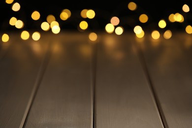 Blurred view of festive lights on wooden table, space for text