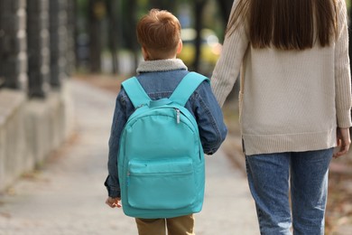 Photo of Young mom taking her son to school, back view