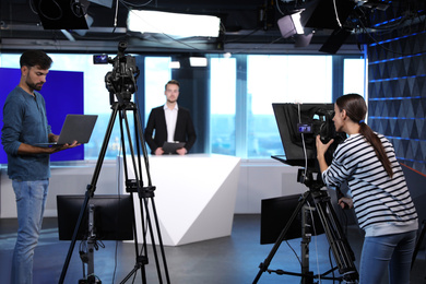 Photo of Presenter, director and video camera operator working in studio. News broadcasting