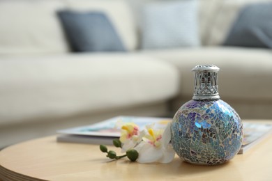 Stylish catalytic lamp with orchid on wooden table in living room, space for text. Cozy interior
