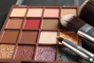 Photo of Colorful eyeshadow palette with brushes, closeup view