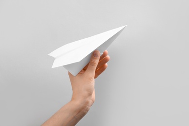 Woman holding paper plane on white background, closeup