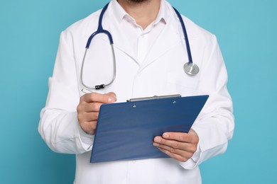 Doctor with stethoscope and clipboard on light blue background, closeup