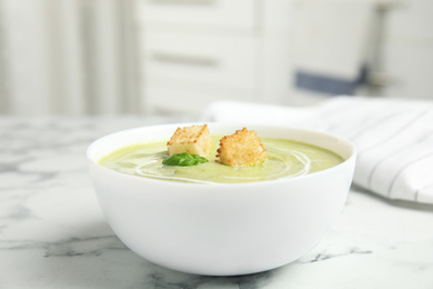 Delicious broccoli cream soup with croutons served on white marble table indoors
