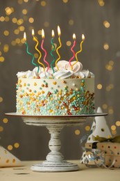 Beautiful birthday cake with burning candles and decor on white table