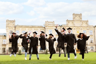 Happy students with diplomas outdoors. Graduation ceremony