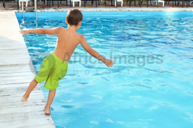 Little child jumping in outdoor swimming pool. Dangerous situation