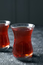 Photo of Glasses of traditional Turkish tea on grey textured table, closeup