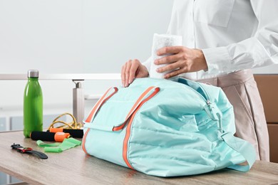 Businesswoman packing sports stuff for training into bag in office, closeup