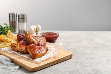 Delicious fried chicken wings served on light grey table, space for text