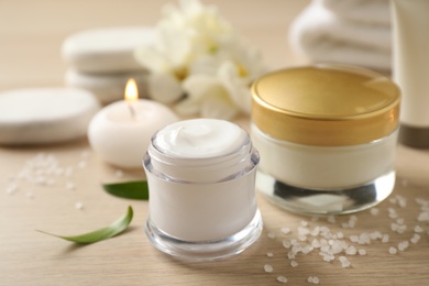 Composition with skin care products and candle on wooden table, closeup