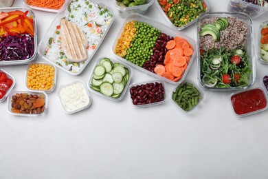 Set of containers with fresh food on white table, flat lay. Space for text