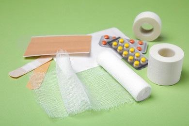 White bandage and medical supplies on light green background