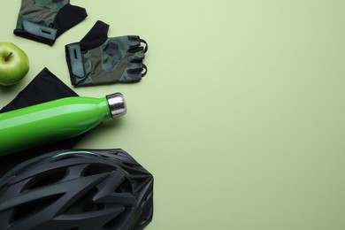 Flat lay composition with different cycling accessories and clothes on light background, space for text