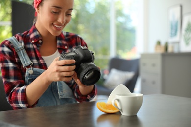 Young photographer taking picture of cups at table indoors, closeup