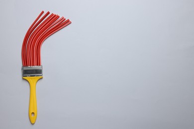 Brush with red straws on light grey background, top view. Space for text. Creative concept
