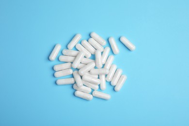 Pile of amino acid pills on light blue background, flat lay