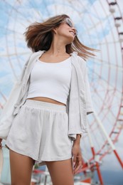 Beautiful young woman near Ferris wheel outdoors