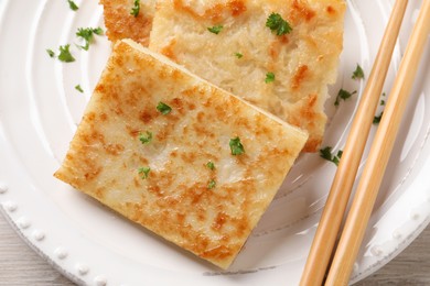 Delicious turnip cake with parsley on plate, top view