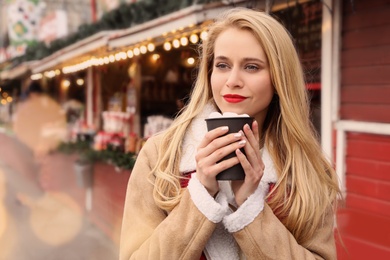 Young woman with hot drink at Christmas fair