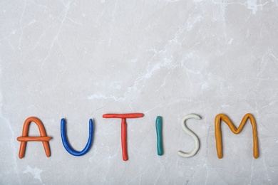 Word AUTISM made of plasticine on light background, top view