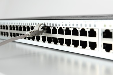 Closeup view of network switch with cable on light background. Internet connection
