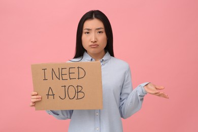 Photo of Unemployed Asian woman holding sign with phrase I Need A Job on pink background