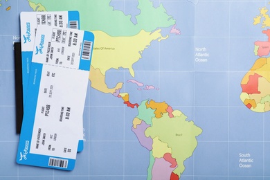 Tickets and passport on world map, flat lay. Travel agency concept