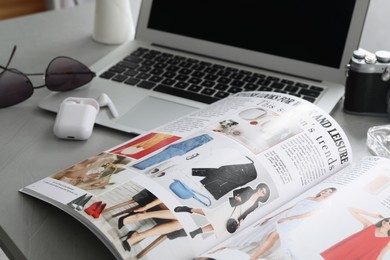 Workplace with fashion magazine on grey table, closeup
